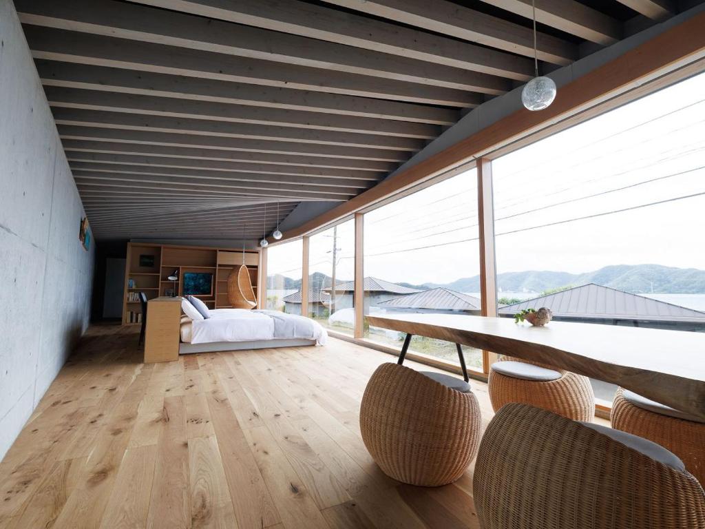 a room with a table and some windows and a bed at Denpaku The Beachfront MIJORA in Amami