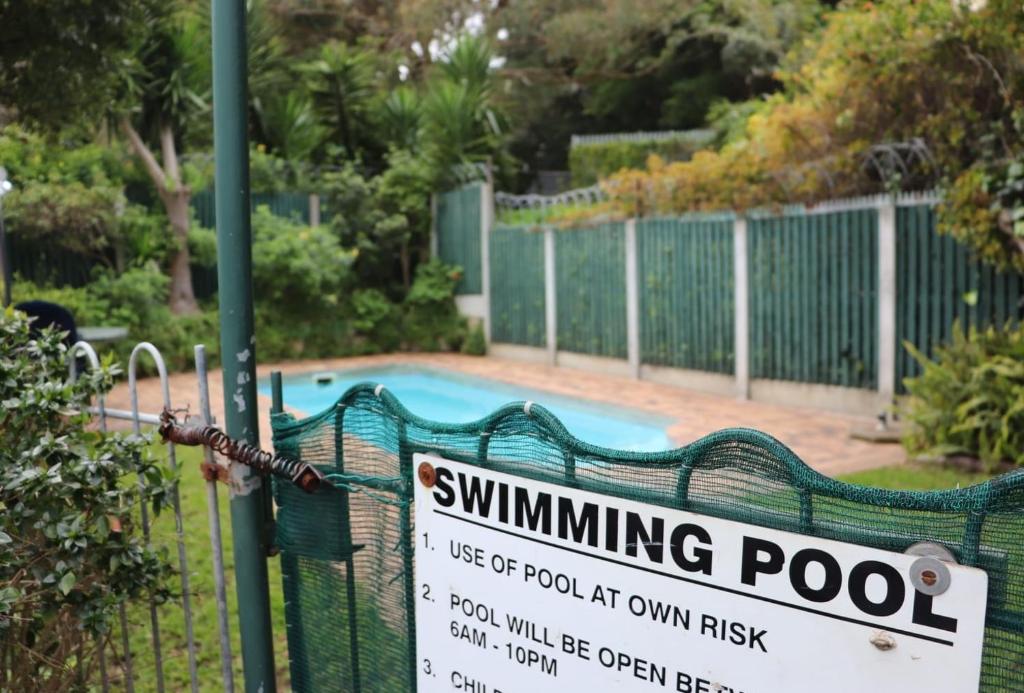 a swimming pool with a sign on a fence at 31 Riverview in Cape Town