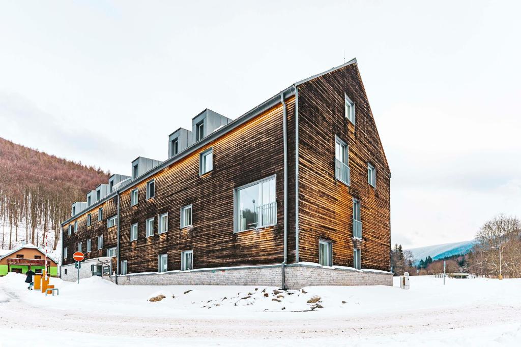 a large brick building in the snow with a stop sign at Apartmany Kouty in Loučná nad Desnou