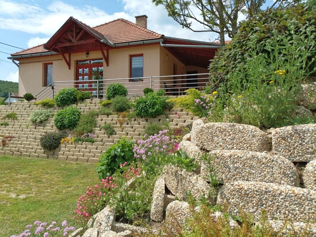 a house with a stone wall in front of a yard at Napfénydomb Vendégház in Mátraszele