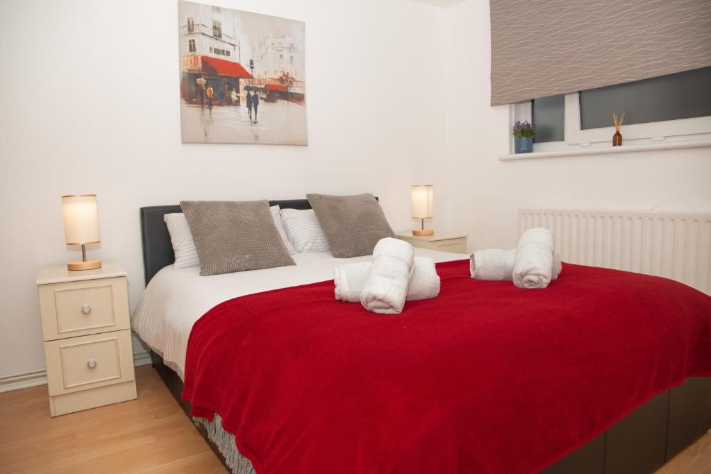 a bedroom with a large bed with red blanket at Large and bright one bedroom apartment with free parking! in London