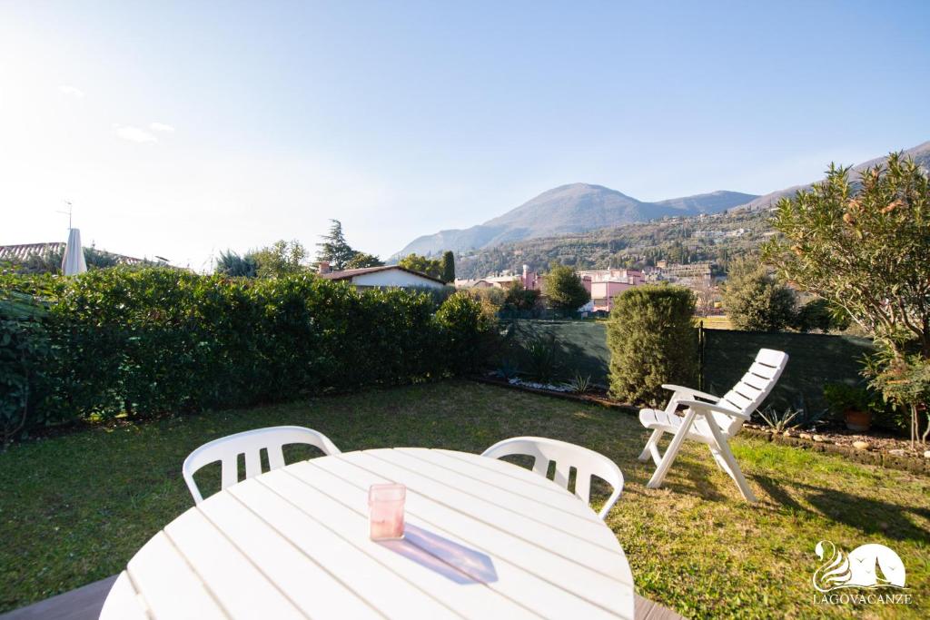 una mesa blanca y sillas en un patio con montañas en Casa Blu, en Toscolano Maderno