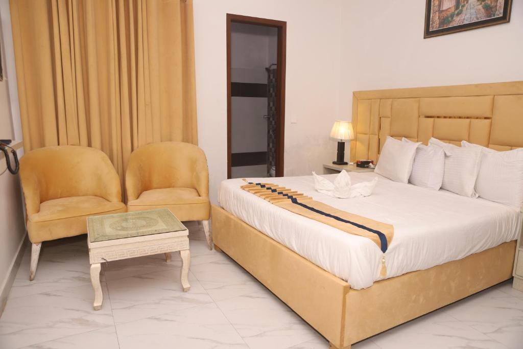 una camera con un grande letto e una sedia di Hotel Royal Comfort a Lahore