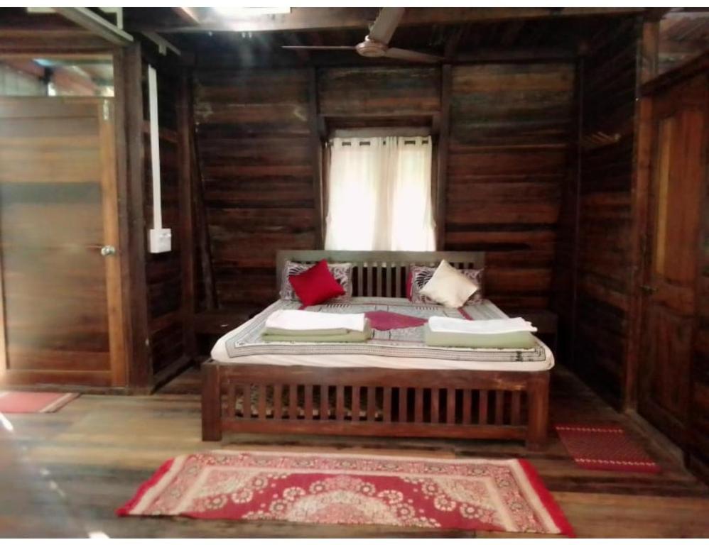 een bed in een houten kamer met een raam bij Tanshikar Spice Farm, Sanguem in Vichondrem
