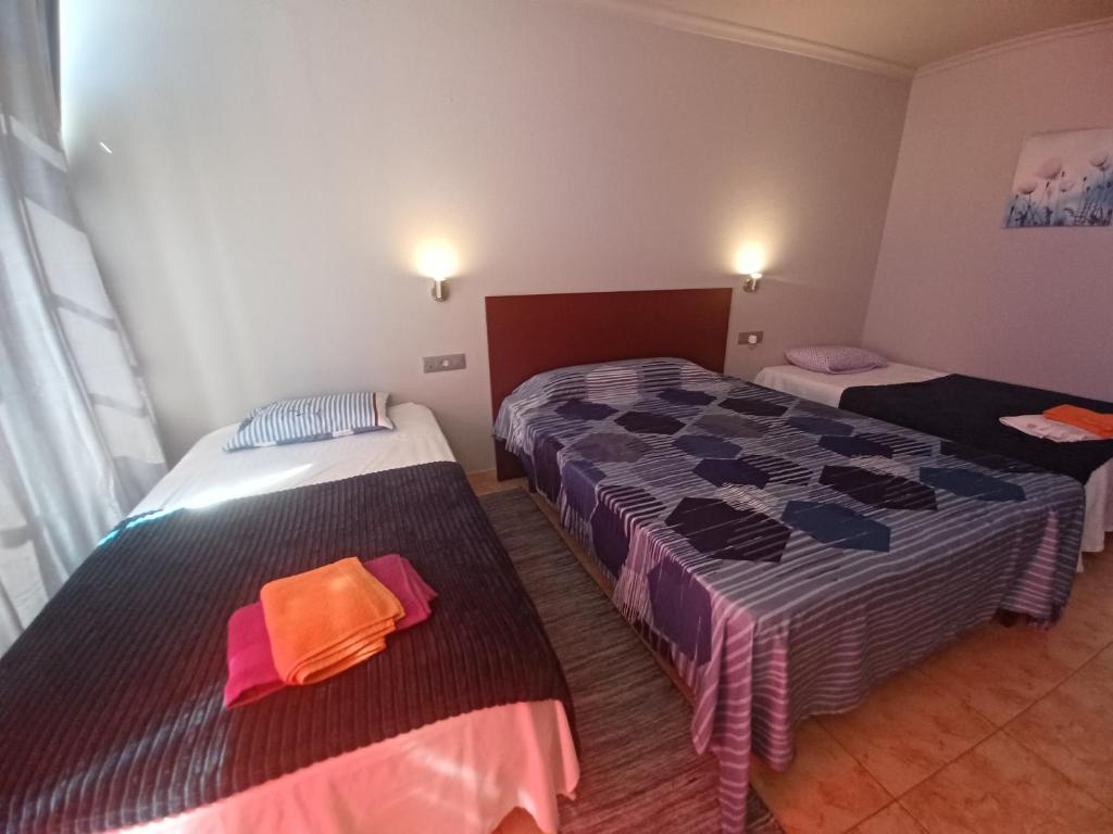 duas camas num pequeno quarto com duas camas em Alojamientos O Camiño em Sigüeiro