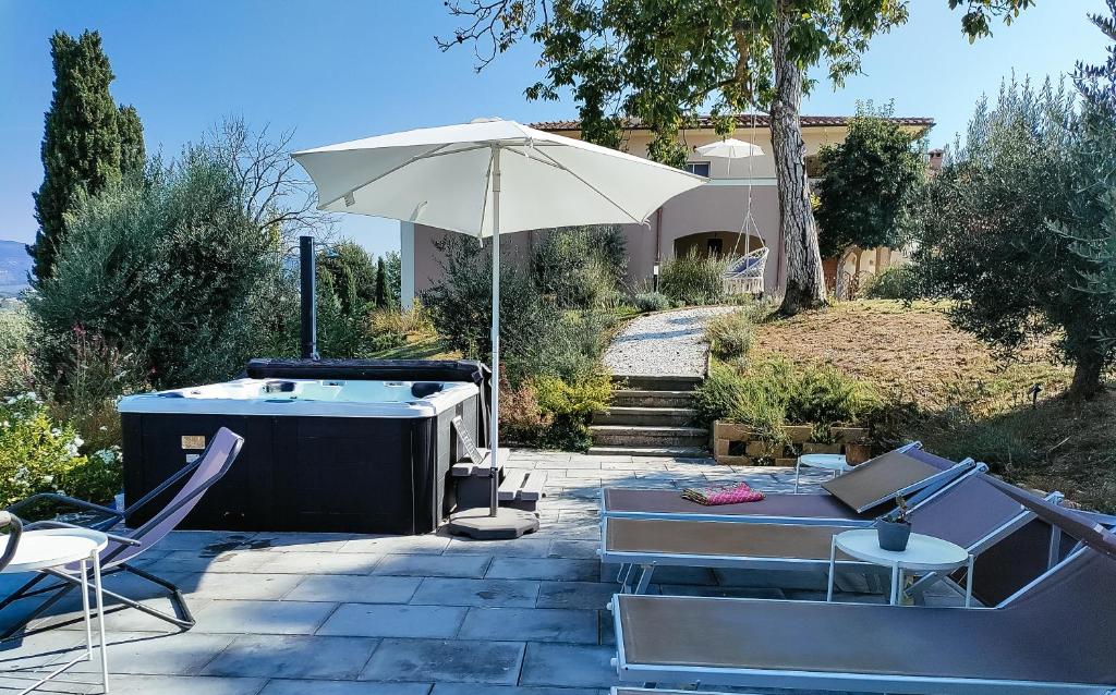 une terrasse avec un bain à remous et un parasol dans l'établissement The Olive Grove in Tuscany, à Toiano