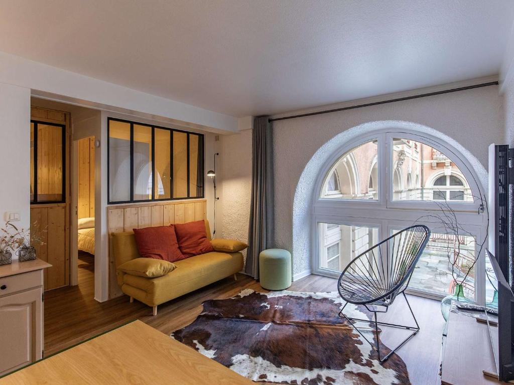 un salon avec un canapé et une fenêtre dans l'établissement Charmant T2 avec cuisine neuve et cave au centre de Cauterets - FR-1-401-278, à Cauterets