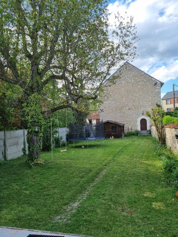 une cour avec un grand bâtiment et un arbre dans l'établissement Maison de charme - accès autonome, à Orléans