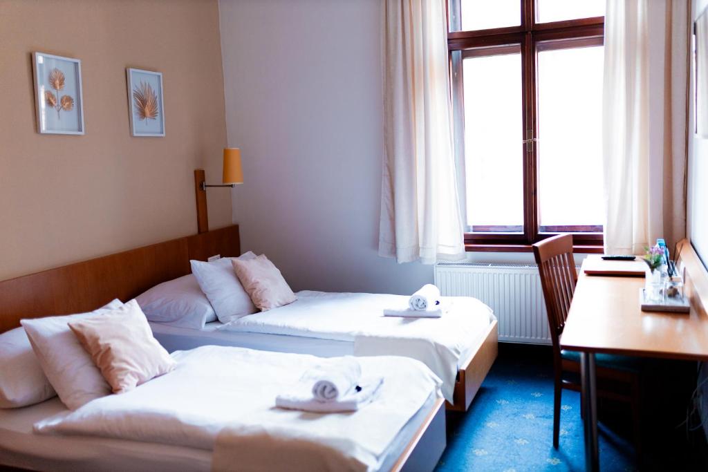 2 Betten in einem Hotelzimmer mit Handtüchern darauf in der Unterkunft Hotel Apollon in Leitmeritz
