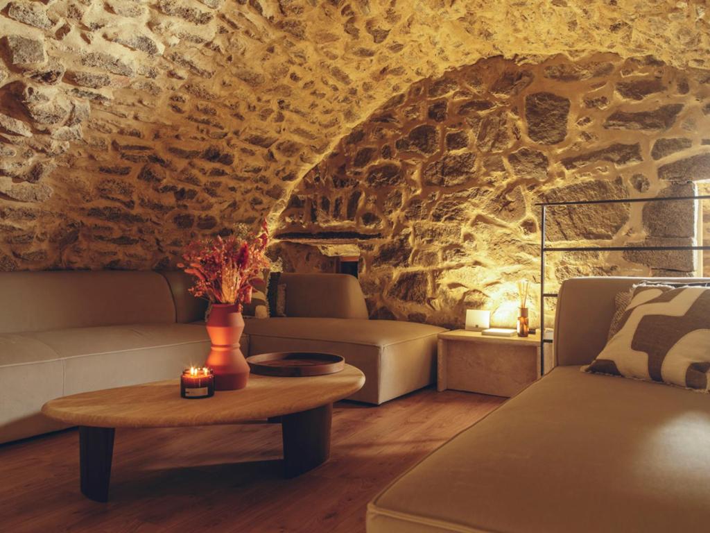 una sala de estar con sofás y una pared de piedra. en La Grotte, en Corbara