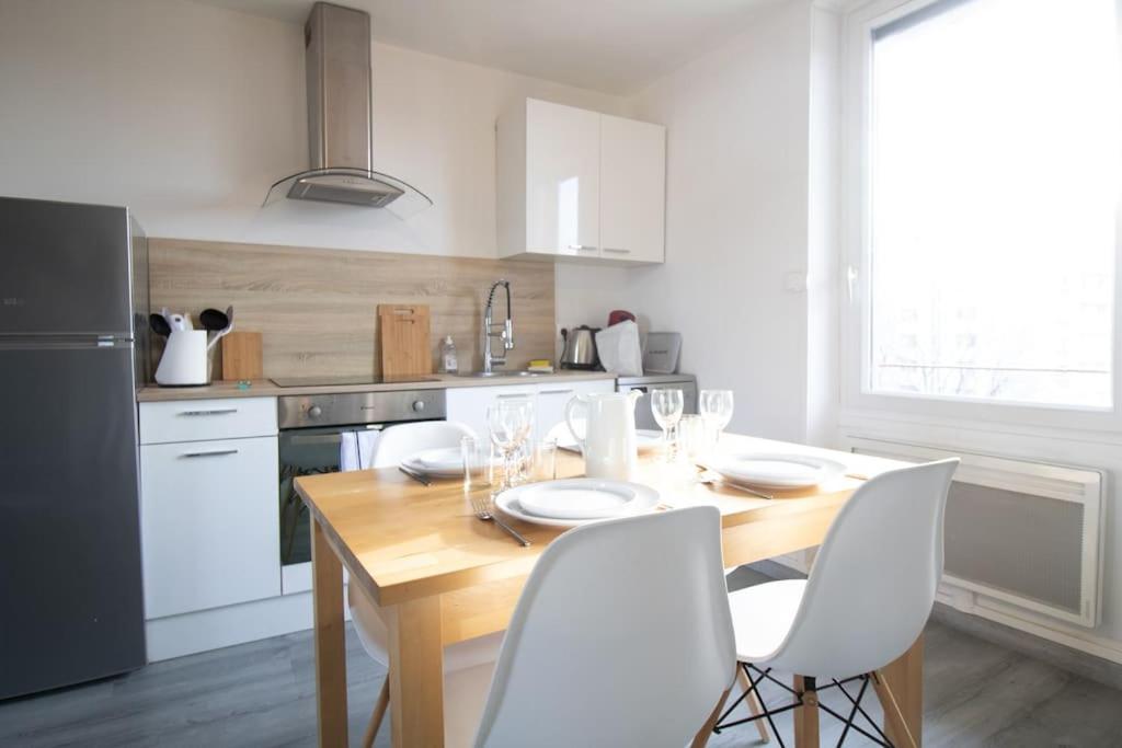 een keuken met een houten tafel en witte stoelen bij L'appartement du VH in Bourg-en-Bresse