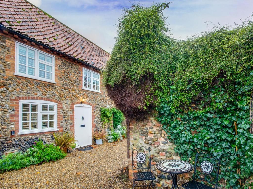 an ivy covered brick house with a white door at 2 Bed in Holt NCC14 in Holt