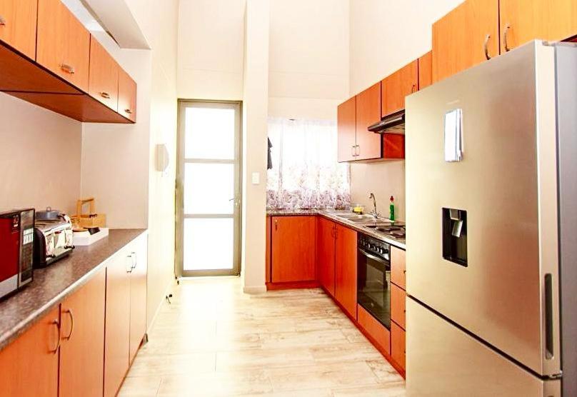 Ongwediva的住宿－MorningSide Fortyfive，厨房配有木制橱柜和冰箱。