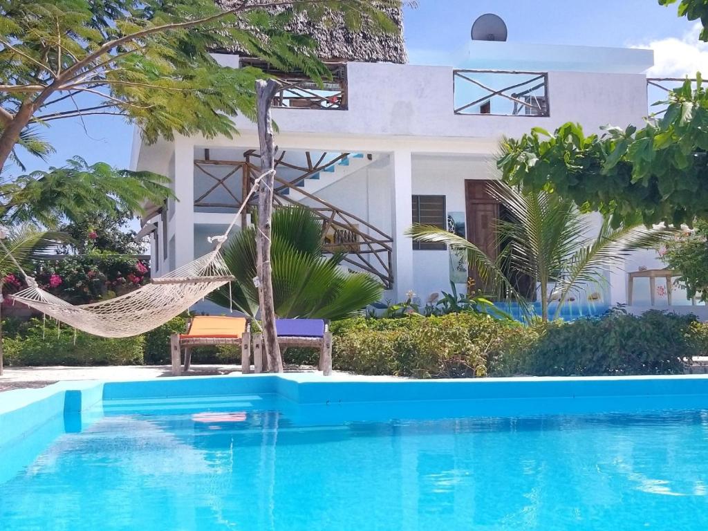 una hamaca junto a una piscina frente a una casa en Villa Francesca Boutique Hotel, en Uroa
