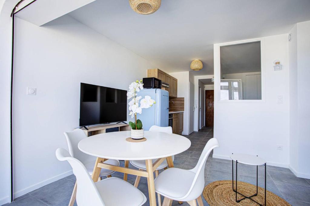 une salle à manger avec une table et des chaises blanches dans l'établissement Appartement T2 vue mer moderne et lumineux -4MELIS47, à Canet