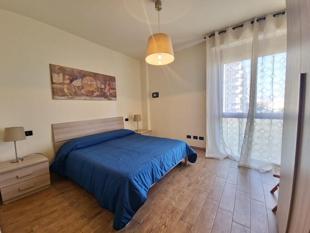 a bedroom with a blue bed and a large window at Residenza Cisanello in Pisa