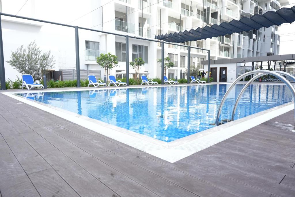 une grande piscine avec des chaises bleues et un bâtiment dans l'établissement Poolside Charm, à Abu Dhabi