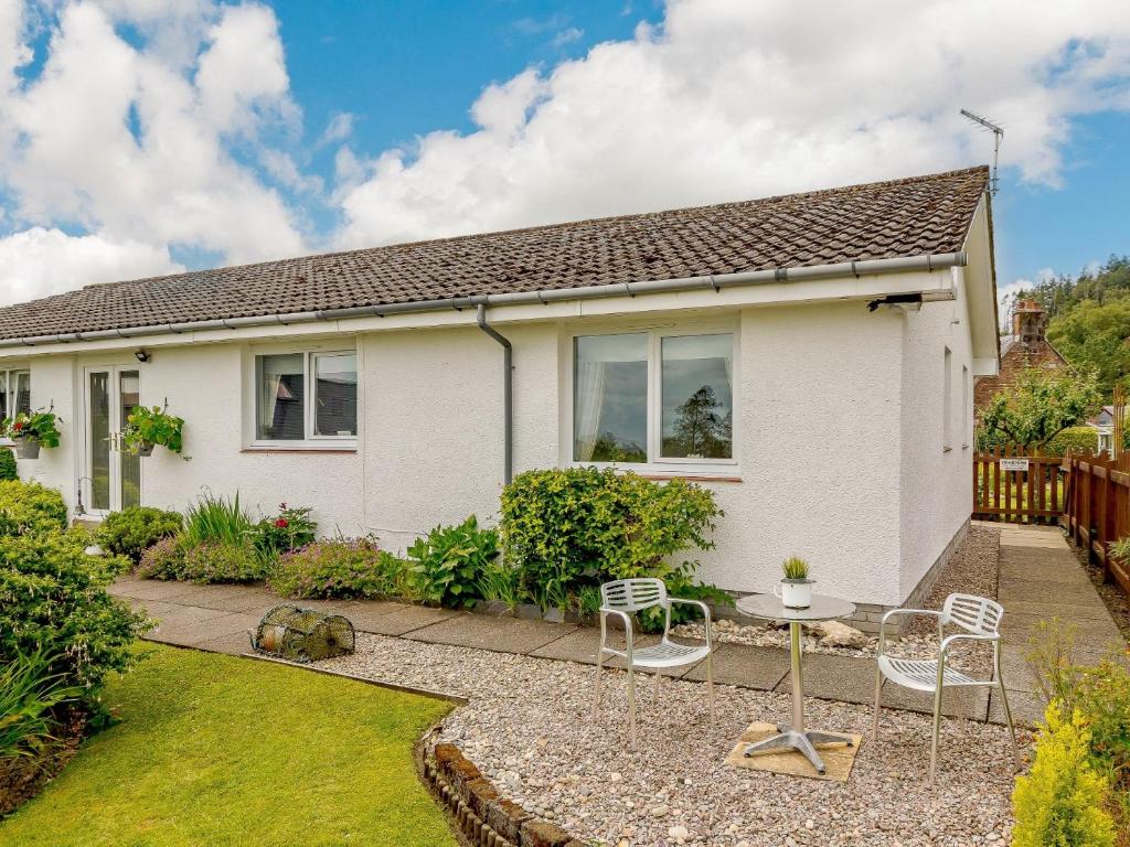 a white house with a table and chairs in the yard at 1 Bed in Brodick CA308 in Brodick