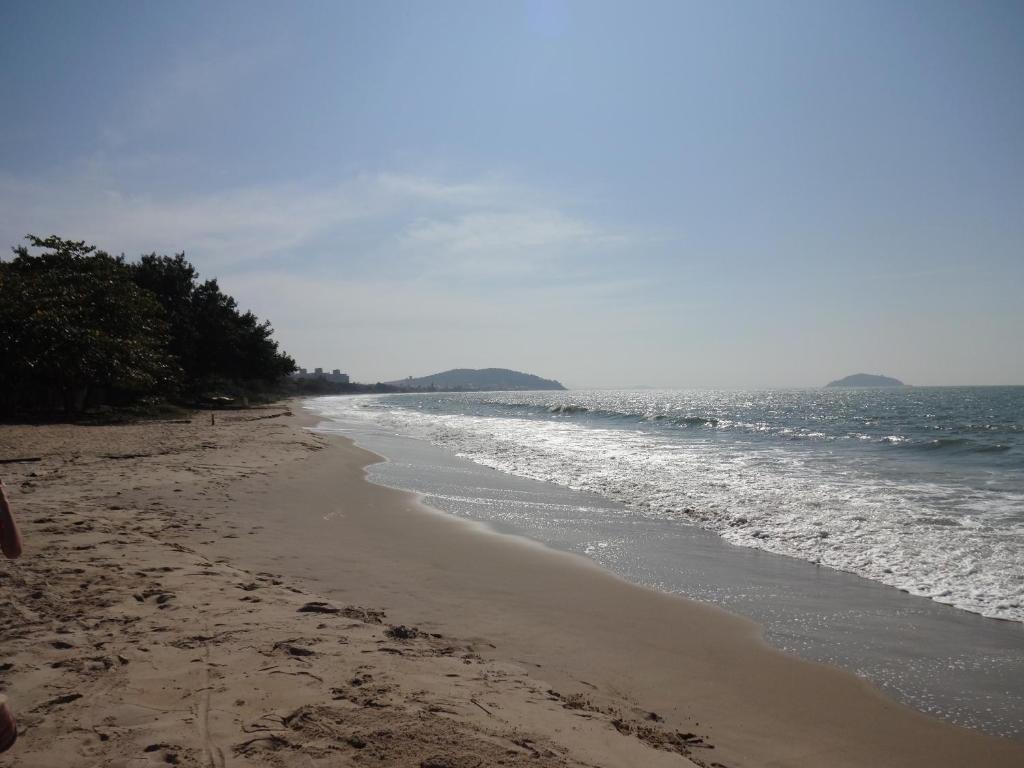 uma praia arenosa com o oceano ao fundo em Apto e Suítes Praia do Itapocoroi em Penha