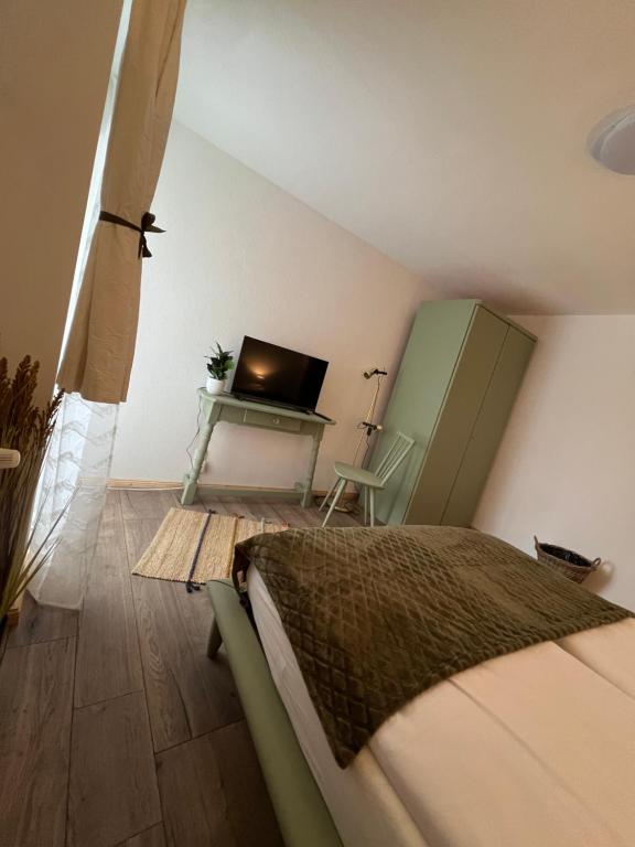 a bedroom with a bed and a desk with a television at Haus zum guten Hirten in Steinsfeld