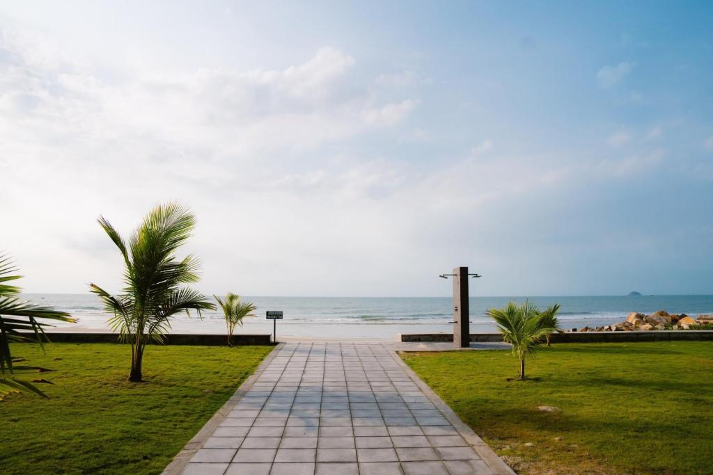 a walkway by the beach with palm trees and a cross at Dat Lanh Beach Resort in Lagi