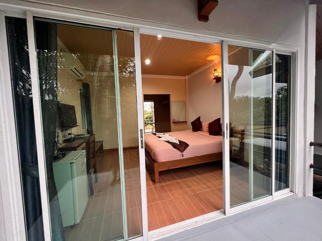 a room with sliding glass doors with a bed at Ingtarn Ressort At thasala in Ban Nai Thung
