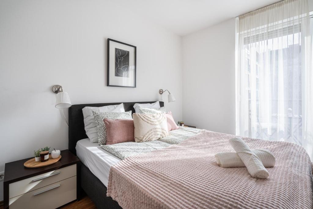 een witte slaapkamer met een groot bed met roze kussens bij Harmony Hideaway Apartment in Boedapest