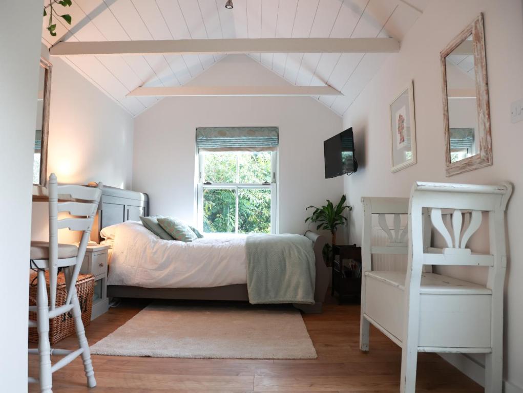 a bedroom with a bed and a desk and a window at Mulberry Studio in Hawkhurst