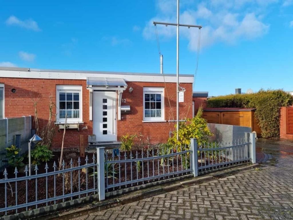 a brick house with a fence in front of it at Haus Ankerliebe in Dornum