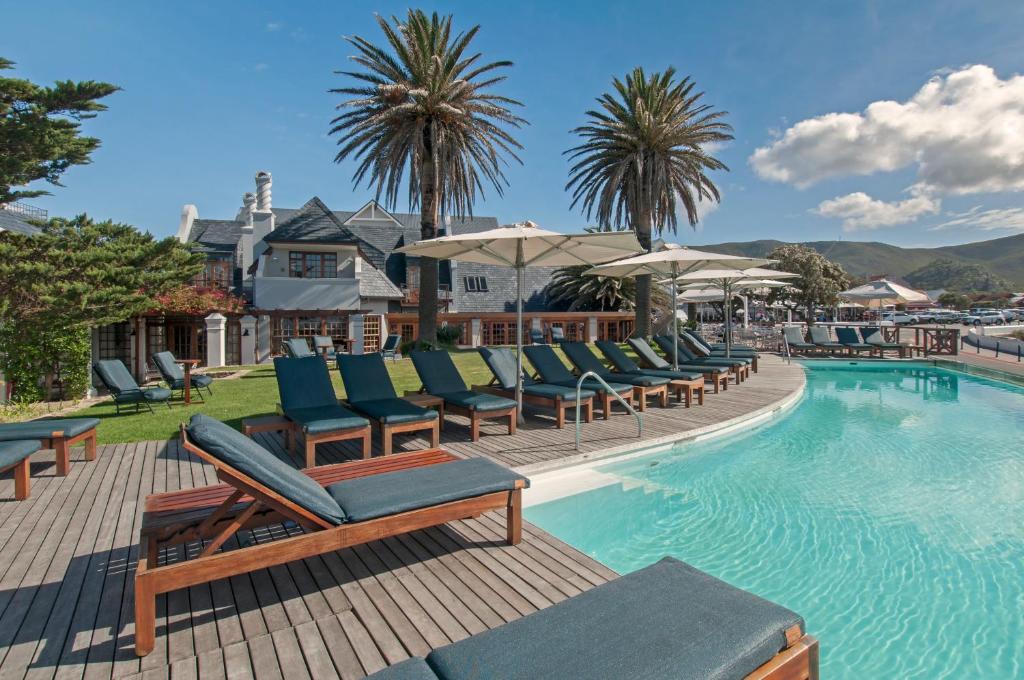 a swimming pool with lounge chairs and umbrellas at Harbour House Hotel - Adventure Pads in Hermanus