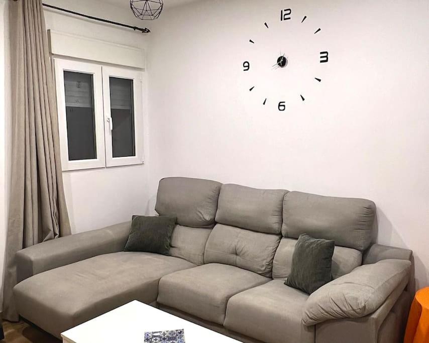 sala de estar con sofá y reloj en la pared en Casa con jardín, en Almería