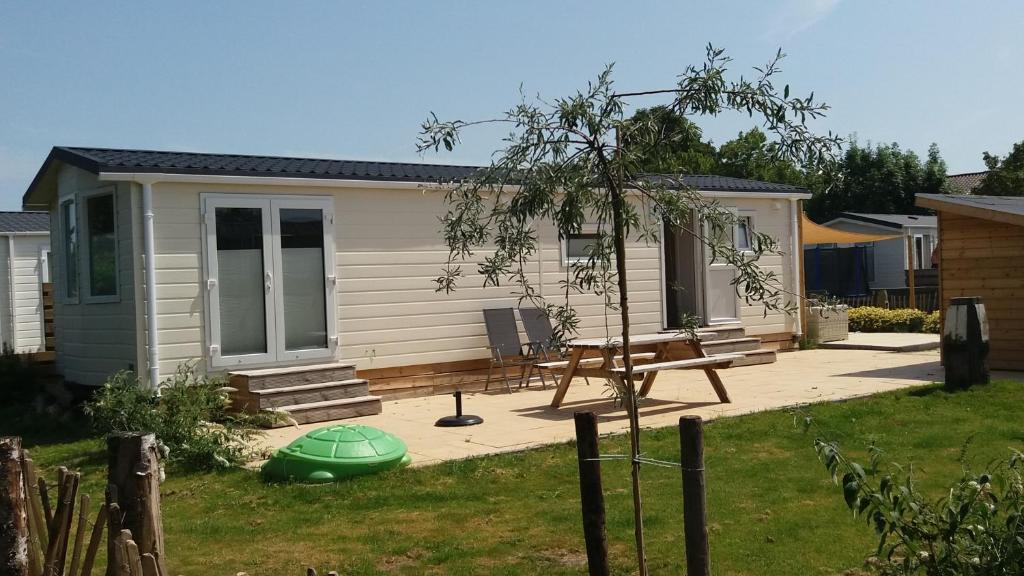 a small house with a picnic table and a bench at Chalet 5a op Recreatiepark De Wielen in Sint Maarten