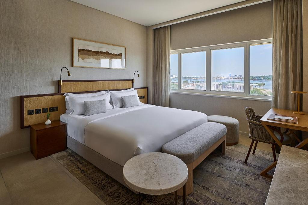 a hotel room with a large bed and a desk at ERTH Abu Dhabi Hotel in Abu Dhabi