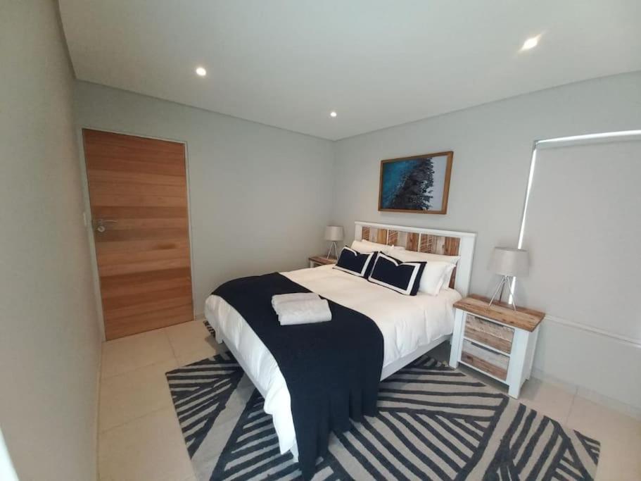 a bedroom with a large bed with a black and white rug at Queens Cove One Bedroom Apt 2 in Knysna