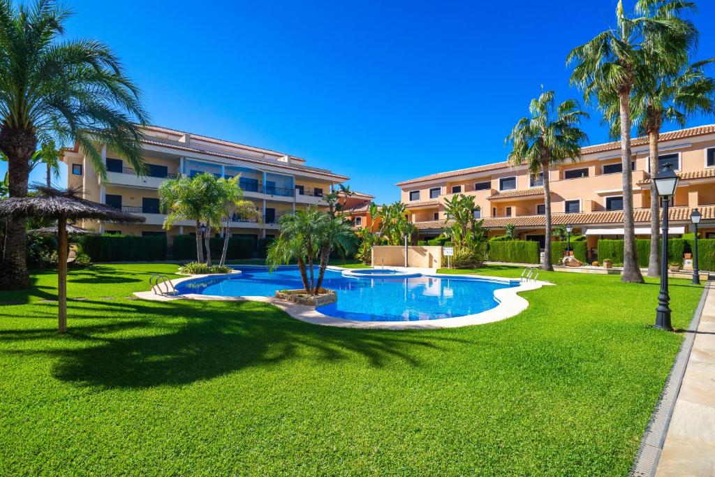 a resort yard with a swimming pool and palm trees at Jardines de Niza in Jávea