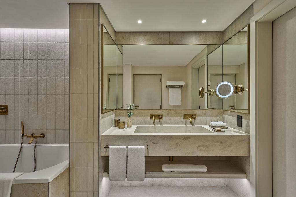 a bathroom with a large sink and a tub at ERTH Abu Dhabi Hotel in Abu Dhabi