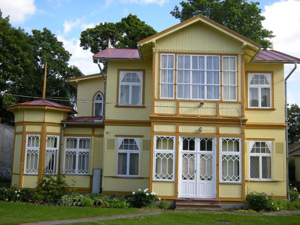 Casa amarilla con puertas y ventanas blancas en Guesthouse Airava, en Jūrmala