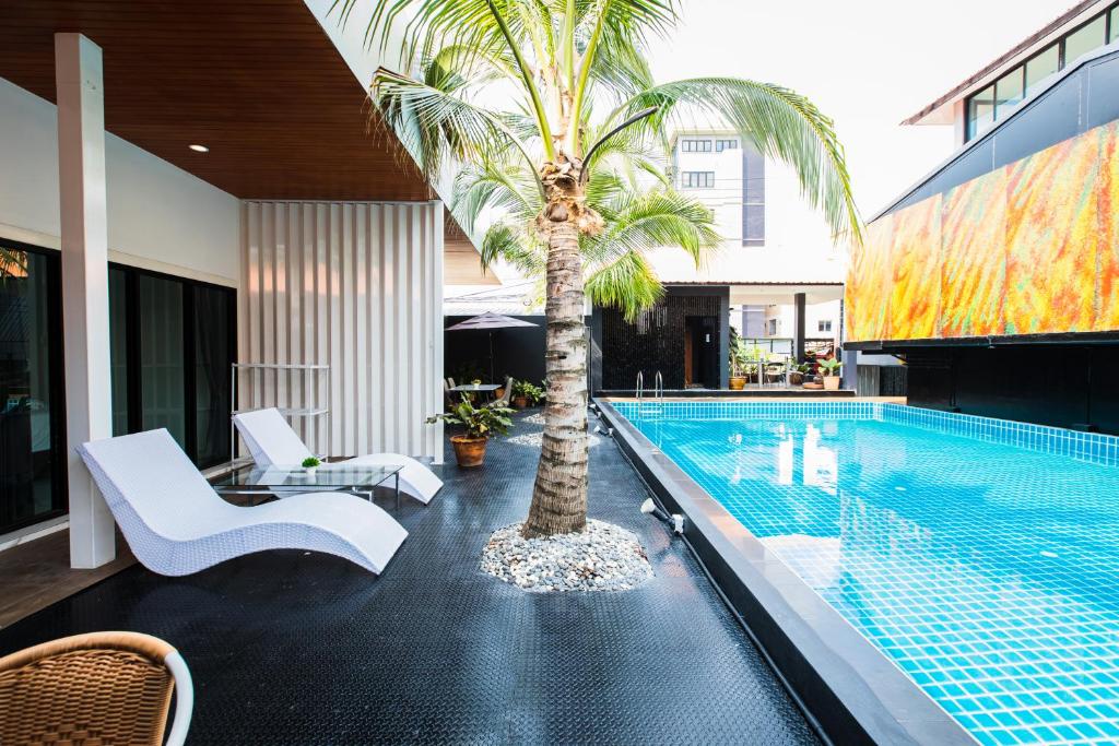 a swimming pool with a palm tree next to a house at PP@Hotel Rangsit in Pathum Thani