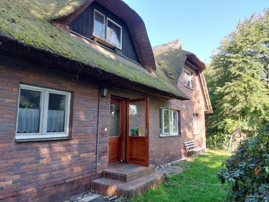 ein Haus mit einem Grasdach und einer Holztür in der Unterkunft Ferienwohnung zwischen Deich und Düne in Dierhagen