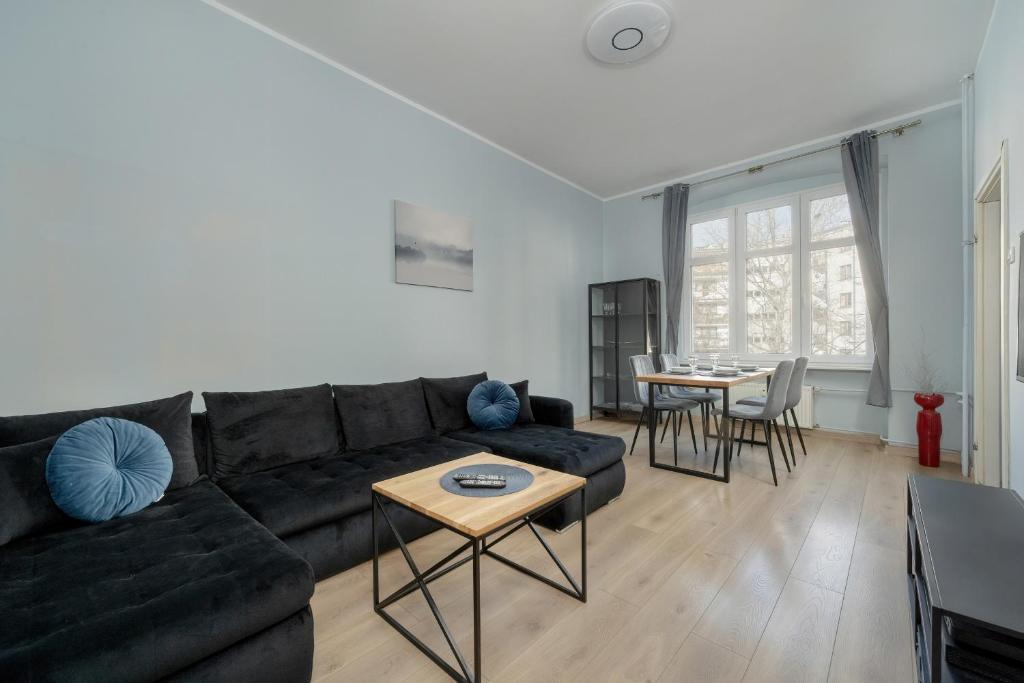 - un salon avec un canapé noir et une table dans l'établissement Spacious 3-Bedroom Apartment Plac Grunwaldzki Wrocław by Renters, à Wrocław