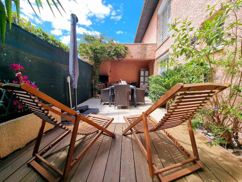 2 chaises et un parasol sur une terrasse en bois dans l'établissement St Cyprien villa de charme avec piscine, à Saint-Cyprien