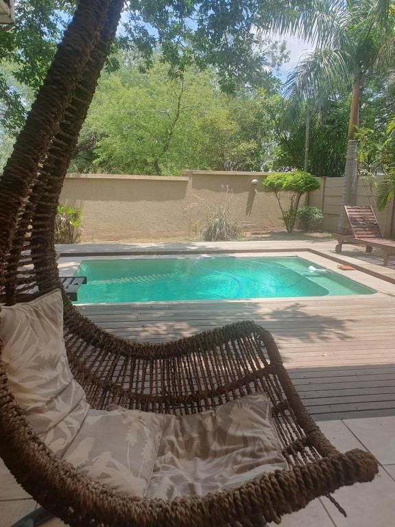 a hammock sitting next to a swimming pool at Gecko Cottages in Hectorspruit