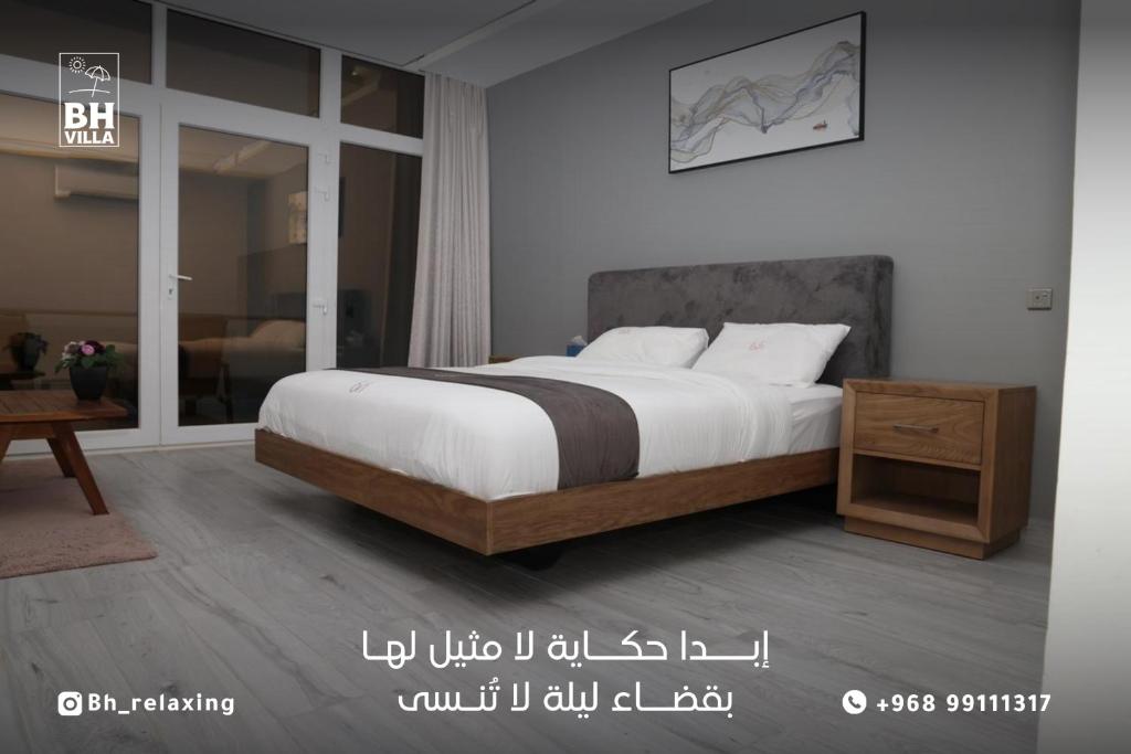 a bedroom with a bed and a wooden night stand at bh villa in Al Ashkharah