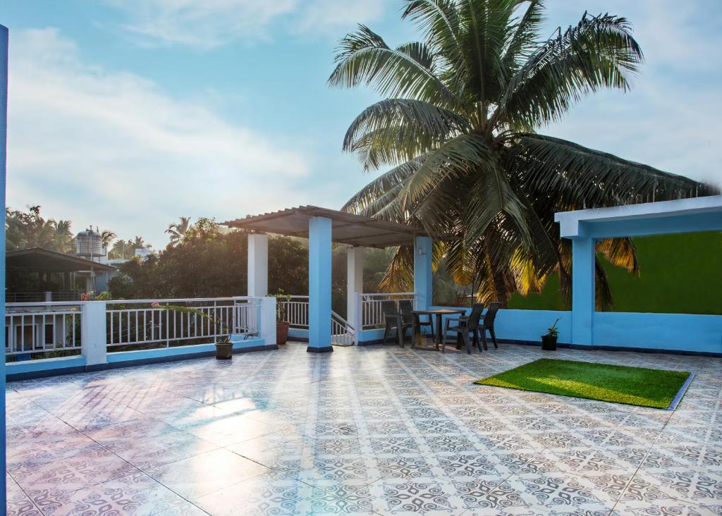 a patio with a table and a palm tree at Whiteboard Homes Siolim in Siolim