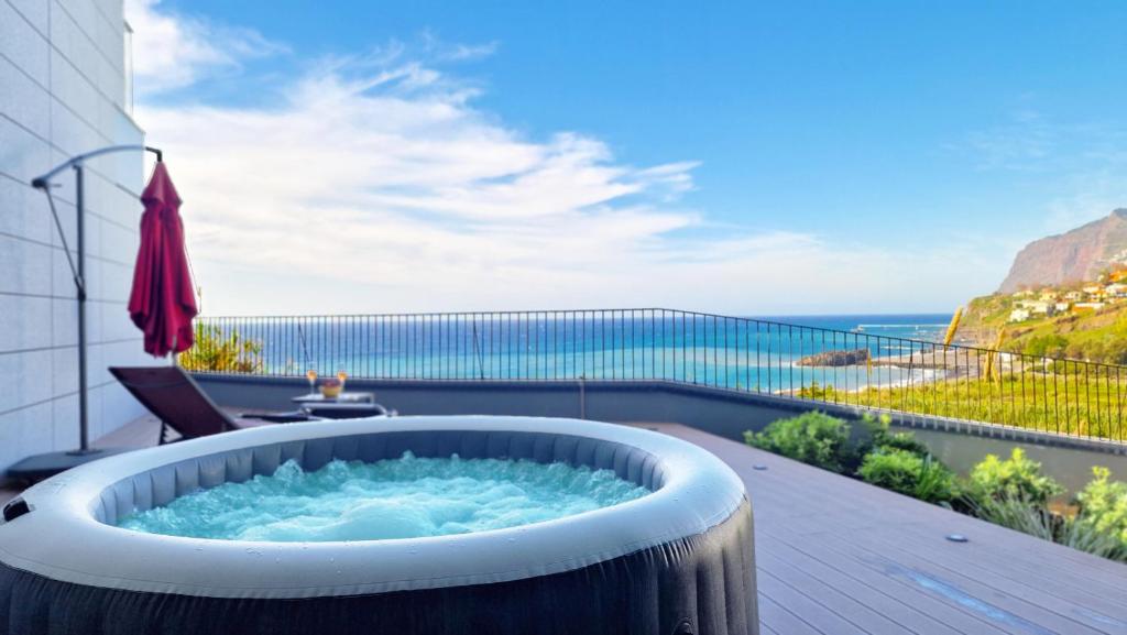 a hot tub on a balcony with a view of the ocean at Over the Cliff Apartment by LovelyStay in Funchal