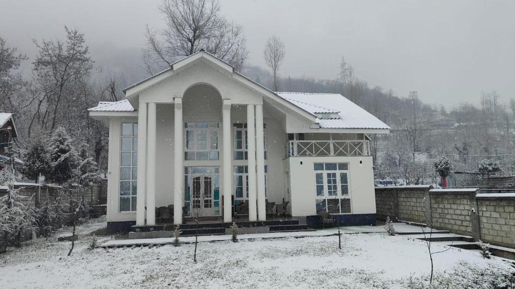 a white house with snow on the ground at Nature's Edge Nishat Srinagar in Srinagar