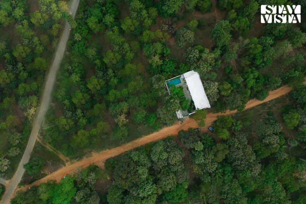 an overhead view of a forest with a house on a dirt road at StayVista at Agam Villa Mahabalipuram in Chennai