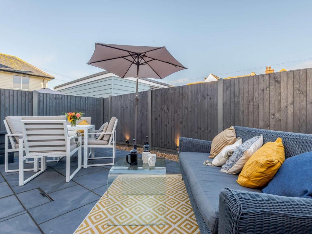 a patio with a blue couch and a table with an umbrella at 1 Bed in Hythe 89967 in Hythe