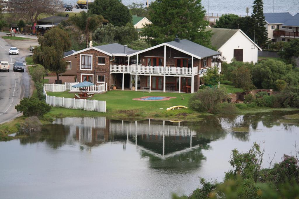 une grande maison avec un lac en face de celle-ci dans l'établissement Salt River Lodge, à Knysna
