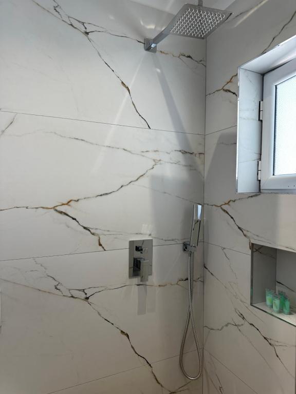 a bathroom with white marble walls and a shower at Arial Lofts in Vlorë